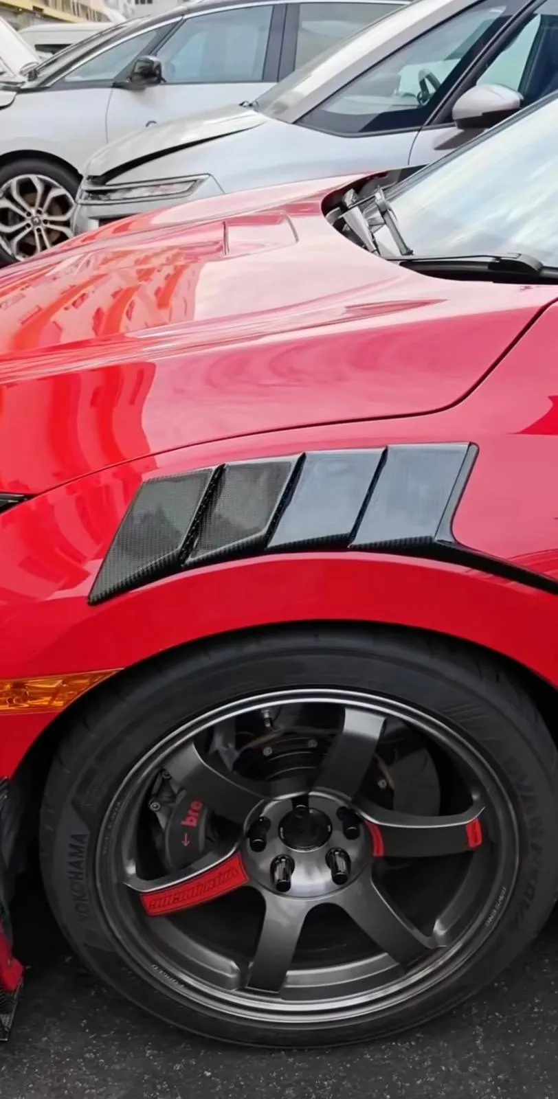 Refinished alloy and carbon wing vents on a red coupe